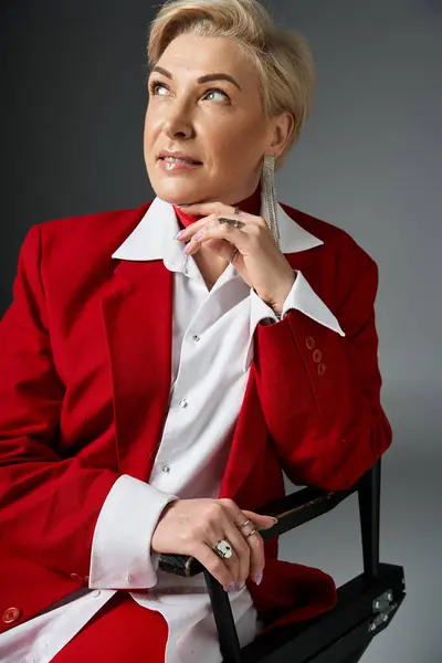An adult woman dressed elegantly in red contemplates while seated, exuding confidence and poise. — Stock Photo