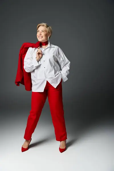 An elegant woman confidently poses in a striking red outfit, showcasing her unique style. — Stock Photo