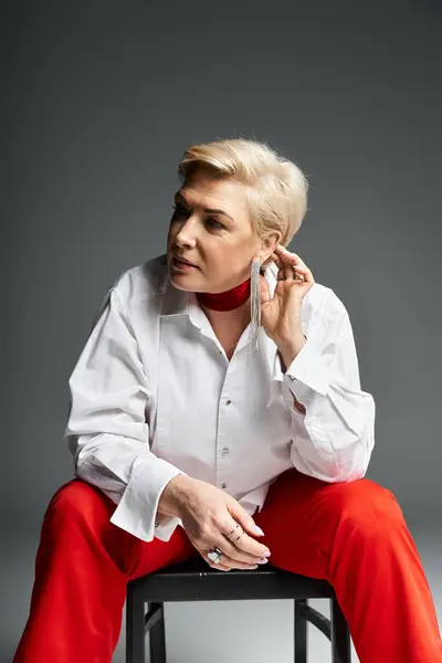 An adult woman exudes sophistication while adjusting her stylish earrings during a fashion shoot. — Stock Photo