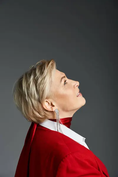 Eine modische Frau in eleganter roter Kleidung blickt mit nachdenklicher Miene nach oben. — Stockfoto