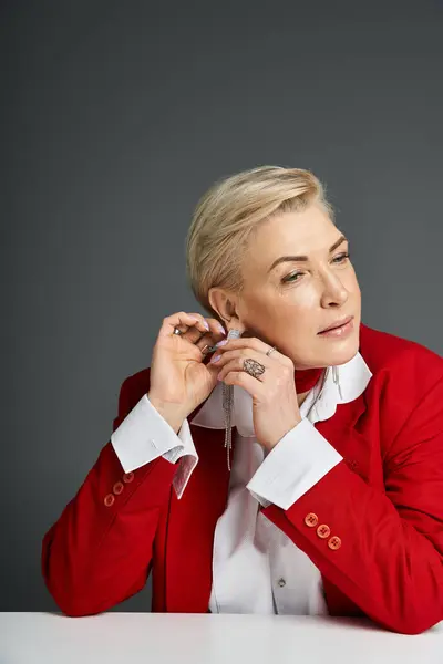 Eine stilvolle Frau passt ihre Ohrringe an und betont ihr schickes Outfit in einem modernen Rahmen. — Stockfoto