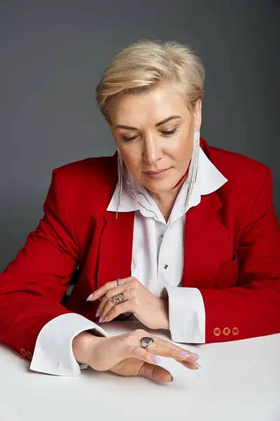 An elegantly dressed woman thoughtfully examines her ring in a modern setting. — Stock Photo