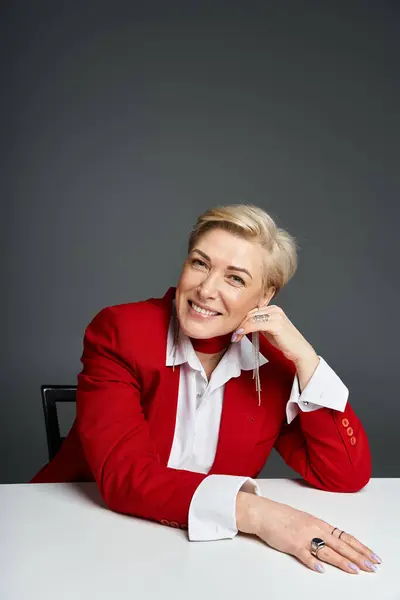 An adult woman in a striking red outfit showcases her poised charm while seated gracefully. — Stock Photo