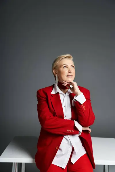 A stylish woman dons a sophisticated red suit, exuding confidence as she ponders creatively. — Stock Photo