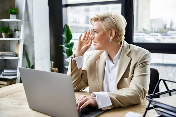 Eine erwachsene Frau mit raffiniertem Sinn für Mode bedient ihren Laptop und strahlt dabei Zuversicht aus. — Stockfoto