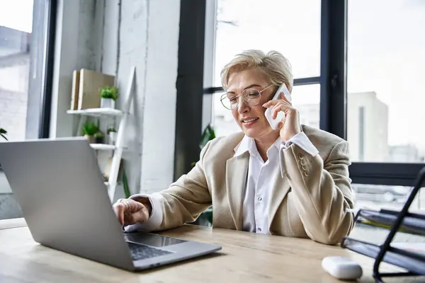 A fashionable woman attentively discusses business matters over the phone while typing. — Stock Photo