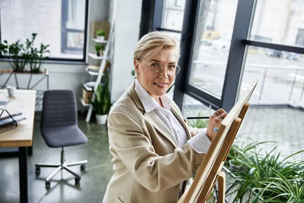 An elegant woman in stylish attire captures creative ideas while sketching in her modern studio. — Stock Photo