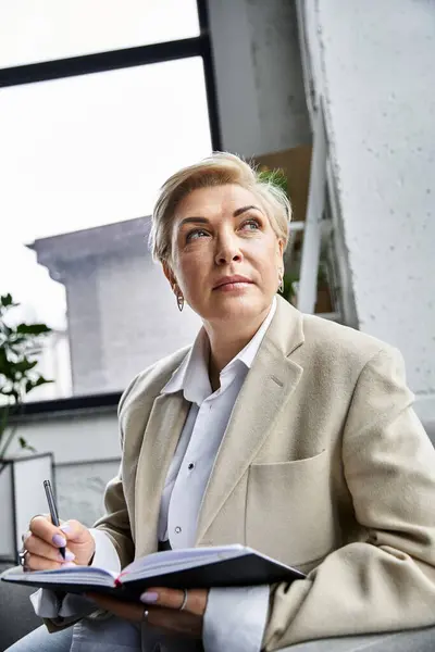 An adult woman dressed elegantly contemplates her thoughts while writing in a notebook. — Stock Photo