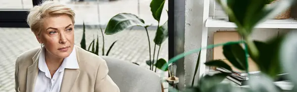 Una donna alla moda in abiti eleganti guarda pensieroso in uno spazio tranquillo giardino interno. — Foto stock