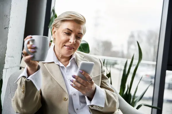 Eine modische Frau nippt am Kaffee und checkt ihr Smartphone, verströmt Charme und Raffinesse. — Stockfoto