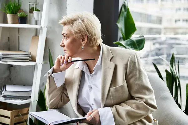 A fashionable woman in sophisticated attire sits pensively, jotting notes in a contemporary office. — Stock Photo