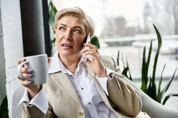 Eine elegante Frau in eleganter Kleidung genießt eine Tasse Kaffee, während sie am Telefon plaudert. — Stockfoto