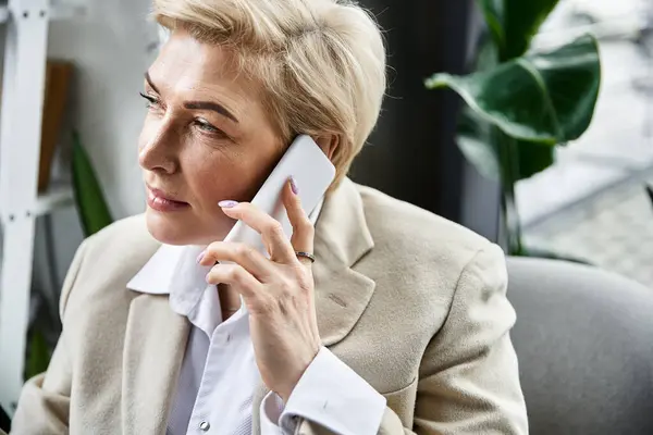 Eine stilvolle erwachsene Frau in schicker Kleidung kommuniziert im Büro am Telefon. — Stockfoto