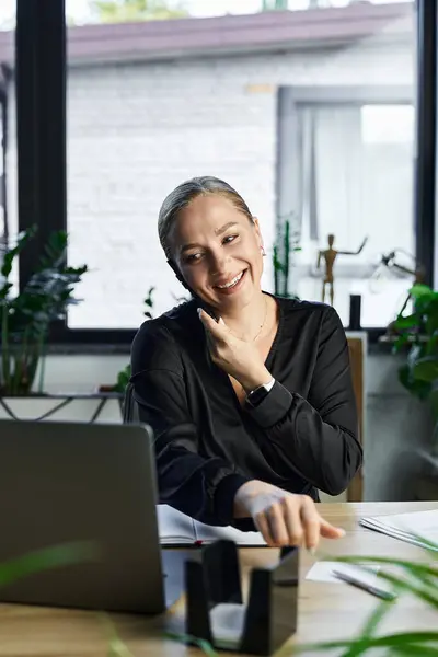 A cheerful young woman is immersed in her work at a stylish office, surrounded by greenery. — Stock Photo