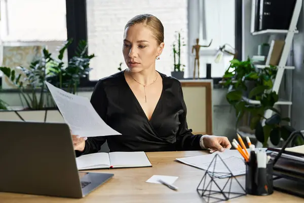 A plus size woman concentrates on her work, reviewing documents in a stylish office environment. — Stock Photo