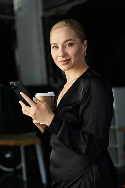 Une jeune belle femme de plus de taille se tient dans un bureau contemporain, engagée avec son smartphone. — Photo de stock