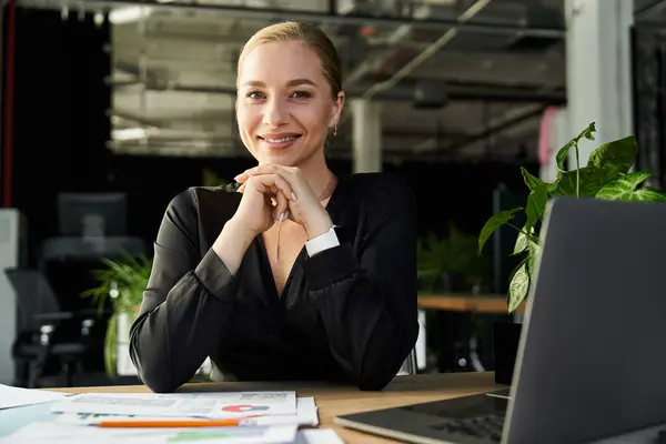 A plus size woman smiles while focused on her work, surrounded by plants and modern office design. — Stock Photo