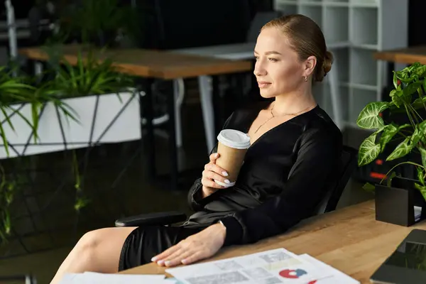 A young plus size woman relaxes at her desk, sipping coffee while working on her tasks. — Stock Photo
