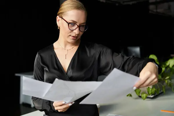 A young plus size woman in a stylish outfit is reviewing documents at her office desk. — Stock Photo