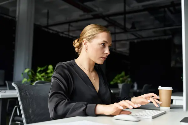 A young beautiful plus size woman concentrates on her work while sipping coffee at her office. — Stock Photo