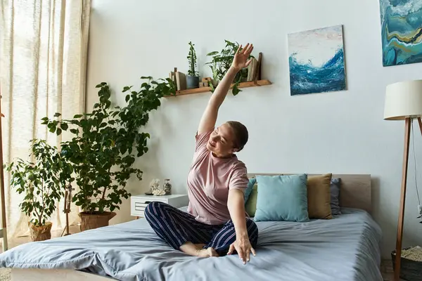 Eine junge, schöne Frau liegt freudig auf ihrem Bett, umgeben von Pflanzen und Kunstwerken. — Stockfoto