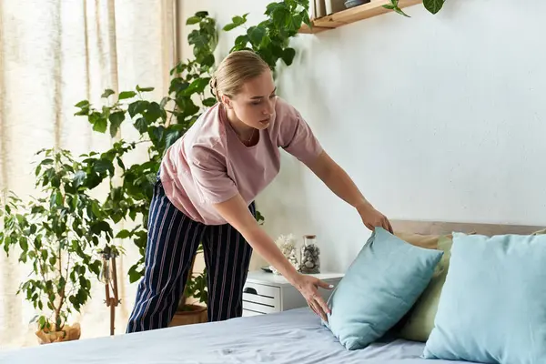 Eine schöne Plus-Size-Frau arrangiert Kissen auf ihrem Bett inmitten eines ruhigen Indoor-Gartens. — Stockfoto