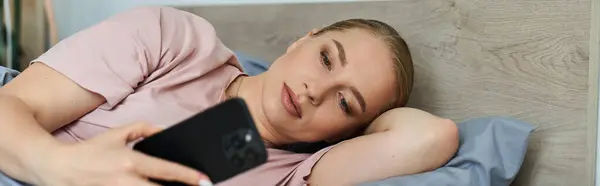 A young beautiful plus size woman enjoys her time at home, scrolling through her smartphone. — Stock Photo