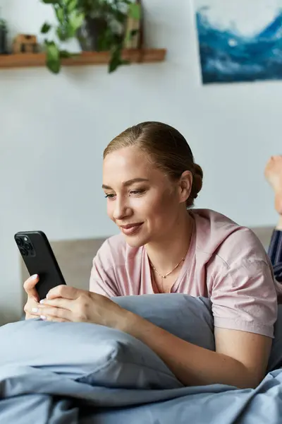A young plus size woman lounges at home, absorbed in her smartphone while relaxing on soft pillows. — Stock Photo