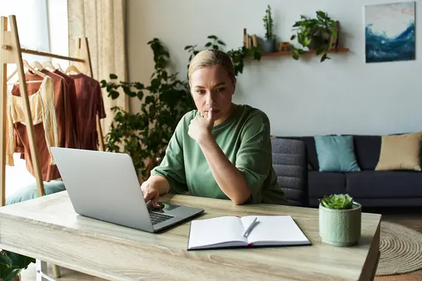 A young plus size woman sits at her desk, deep in thought while working on her laptop. — Stock Photo