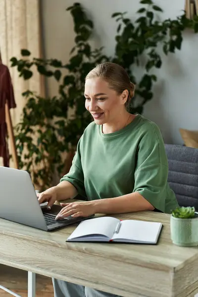 A cheerful plus size woman engages in her work at home, surrounded by plants and cozy decor. — Stock Photo