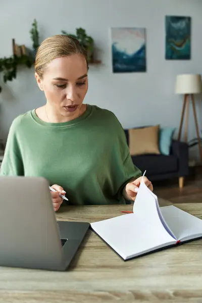 A young beautiful plus size woman actively writes in her notebook, focused and inspired at home. — Stock Photo