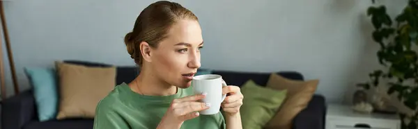 Une jeune femme de taille plus savourant une boisson chaude tout en se relaxant dans son espace de vie confortable. — Photo de stock