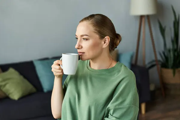 A young plus size woman relaxes at home, savoring a warm cup of coffee in a cozy setting. — Stock Photo