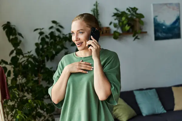A young, beautiful plus size woman at home smiles while talking on the phone, radiating happiness. — Stock Photo