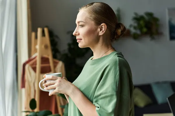 A woman savors her tea while gazing out the window, embracing a moment of tranquility. — Stock Photo
