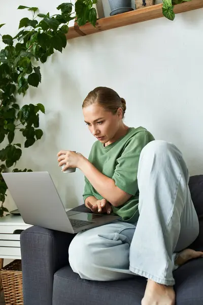 A young plus size woman relaxes with a laptop while sipping a drink in her cozy home setting. — Stock Photo