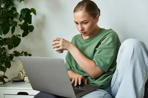 A young beautiful plus size woman enjoys her cozy home setup while working on a laptop. — Stock Photo