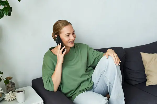 A young beautiful plus size woman relaxes on her couch, smiling and talking on her phone. — Stock Photo
