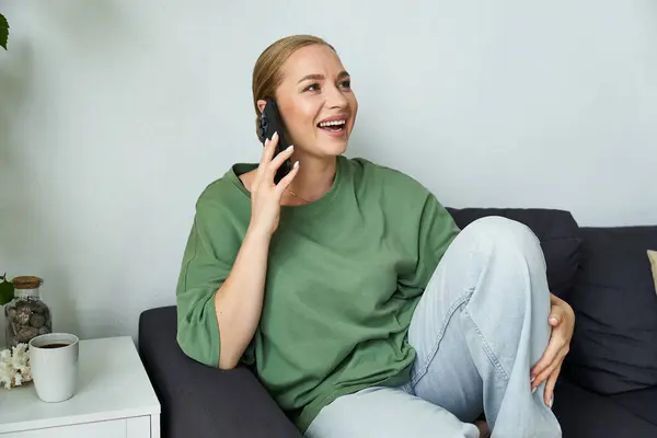 A young, beautiful plus size woman smiles and chats comfortably on her couch. — Stock Photo