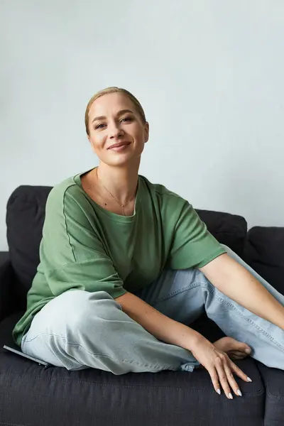 A cheerful woman relaxes comfortably on her couch, exuding warmth and style at home. — Stock Photo
