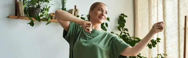 A young beautiful plus size woman dances happily in her cozy home, surrounded by greenery. — Stock Photo