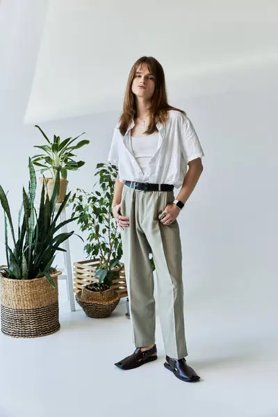 A fashionable young man poses confidently amidst indoor plants, embodying contemporary style. — Stock Photo