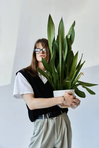 A fashionable young man holds a large tropical plant while dressed in trendy attire, exuding style. — Stock Photo