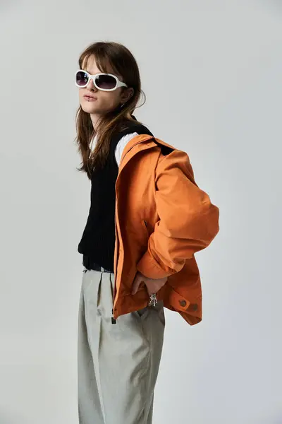 Un joven vestido con ropa de moda posa con confianza sobre un telón de fondo minimalista. - foto de stock