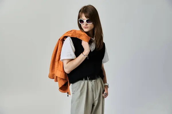 A young, fashionable guy exudes confidence, showcasing his trendy outfit and orange jacket. — Stock Photo