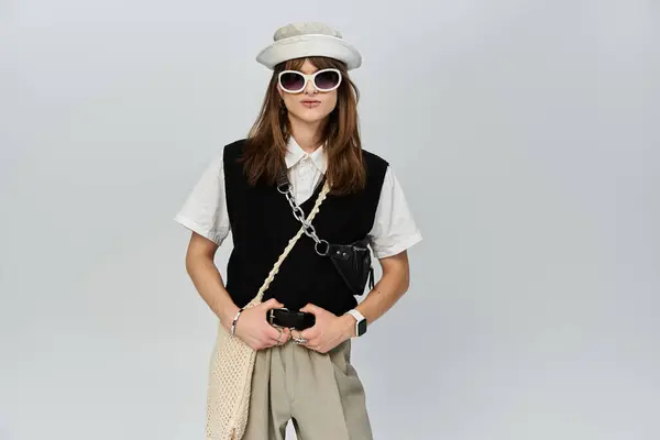 A young man dressed in contemporary fashion stands confidently against a light backdrop. — Stock Photo