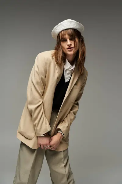 Молодой человек излучает уверенность в модном наряде, позируя на нейтральном фоне. — стоковое фото