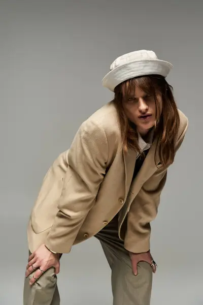 A young stylish individual leans playfully, exuding confidence in trendy, relaxed attire. — Stock Photo
