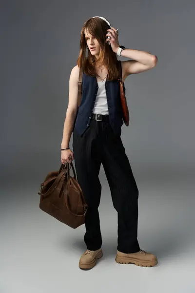 A confident young man exudes style as he poses with fashion forward flair, carrying a bag. — Stock Photo