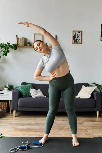 A young sportive woman in leggings stretches in her cozy living room, focusing on her fitness routine. — Stock Photo